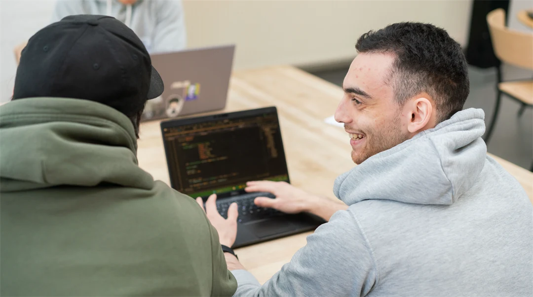 A man sitting at a laptop and smiles. 