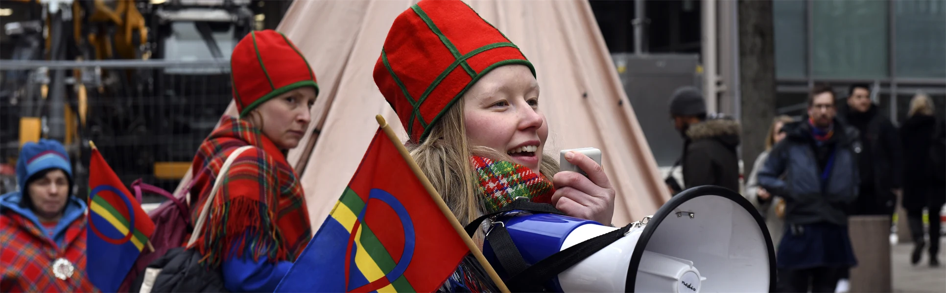 Kvinna håller en sameflagga och talar i en megafon.