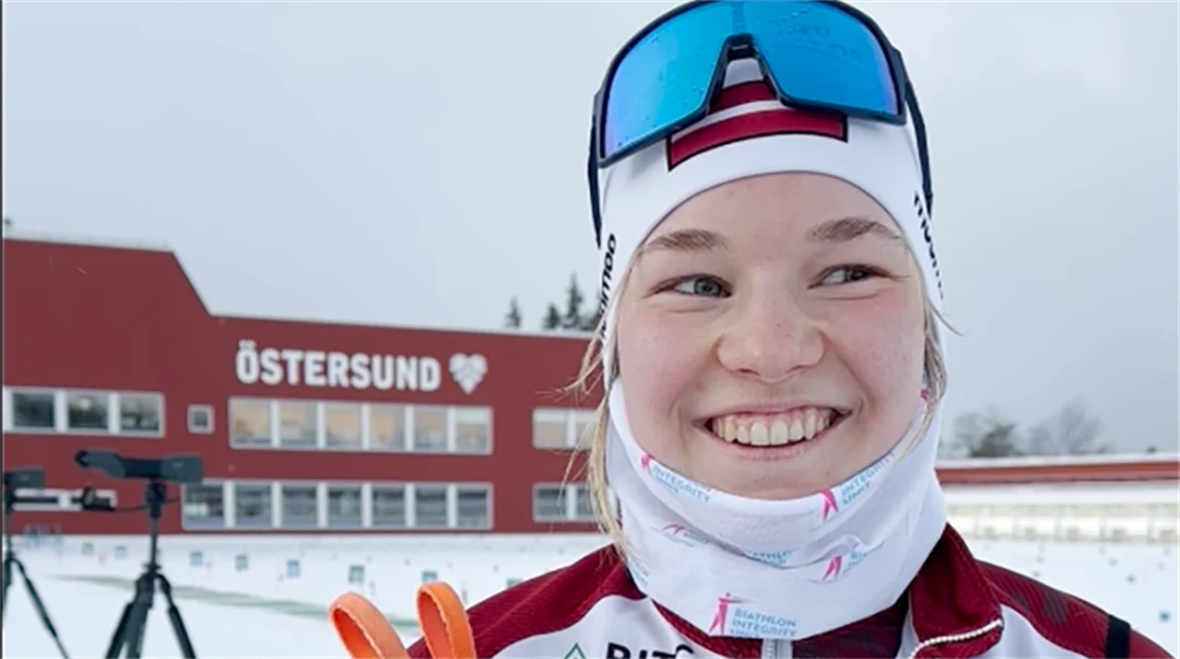 Smiling woman at a biathlon stadion.