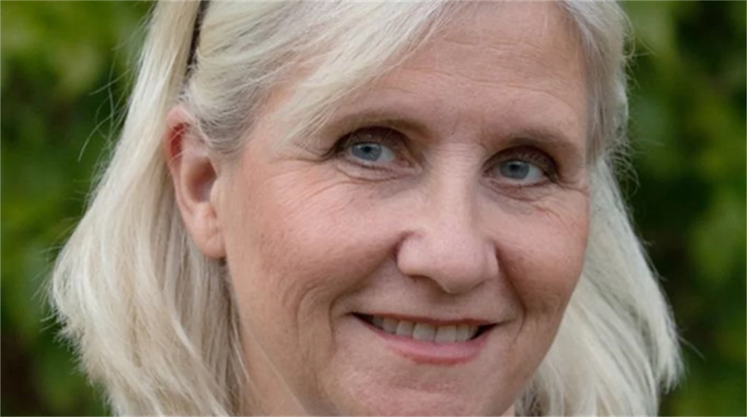 En kvinna utomhus i vit tröja och grå kavaj