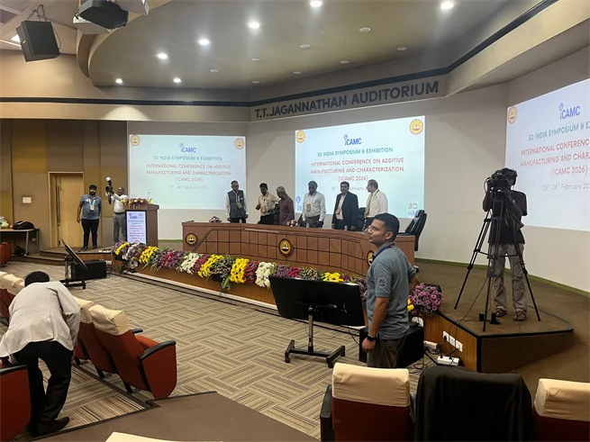 About ten people stand behind a desk with screens behind them.