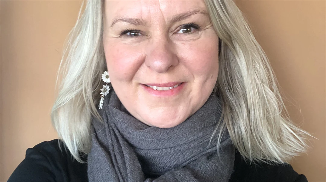 Ett porträttfoto av en blond kvinna mot en ljusbeige bakgrund