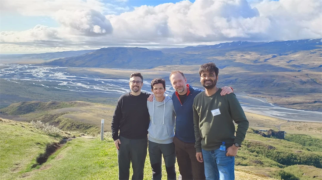 Four people stand together with a view of a valley in the background.