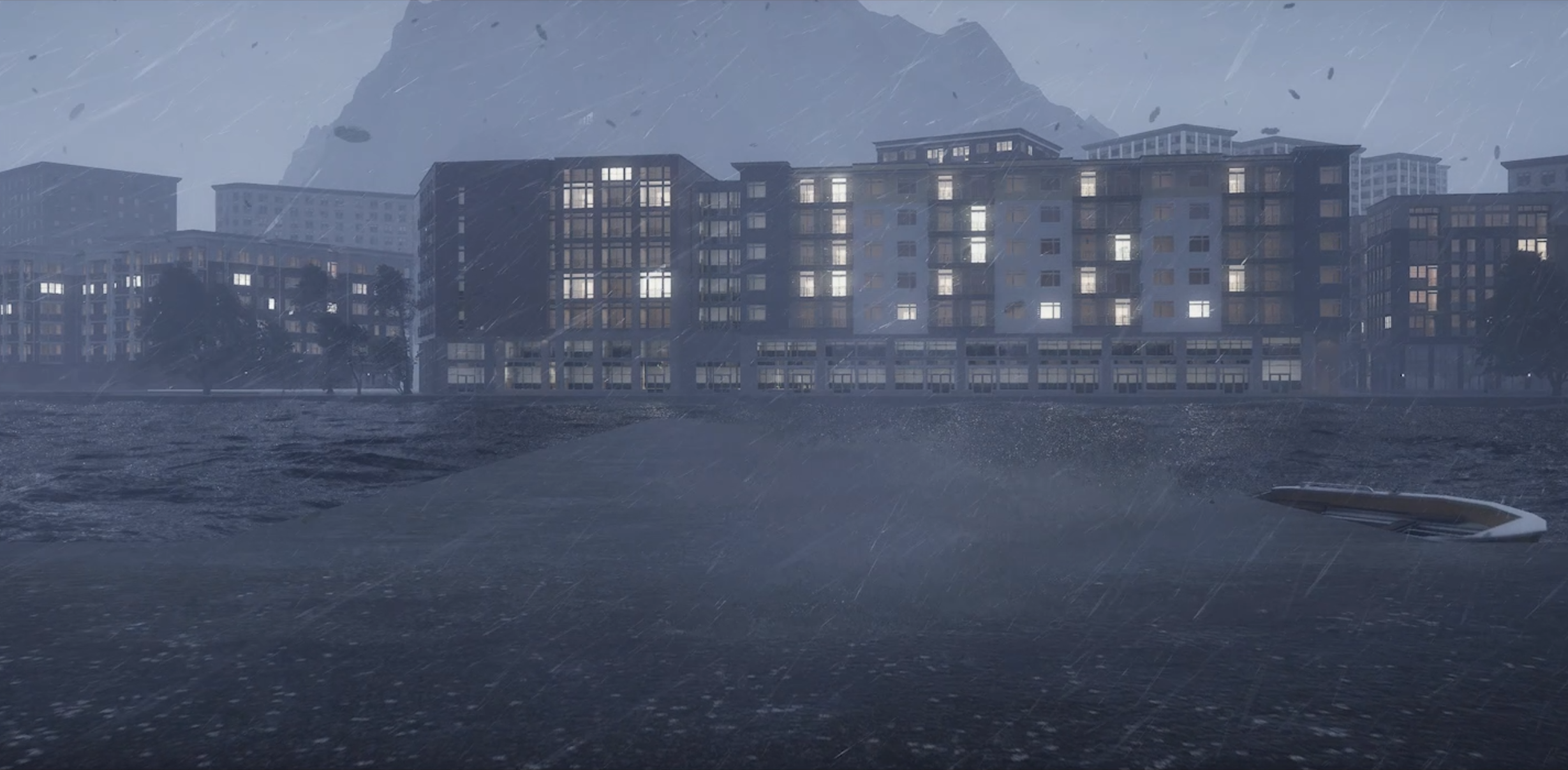 Ett stadsområde vid vattnet med höghus och berg i bakgrunden under regnigt väder.