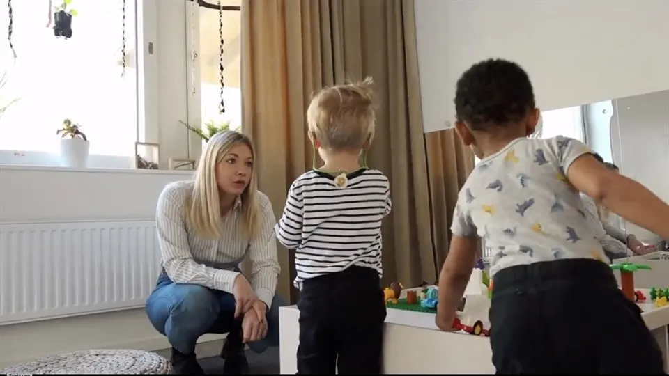 Kvinna sitter på huk , två barn leker