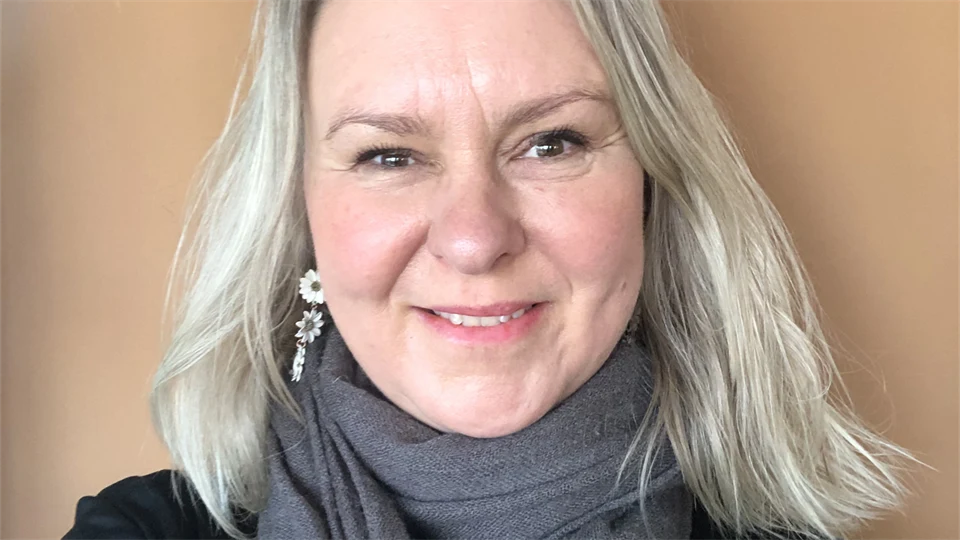 Ett porträttfoto av en blond kvinna mot en ljusbeige bakgrund