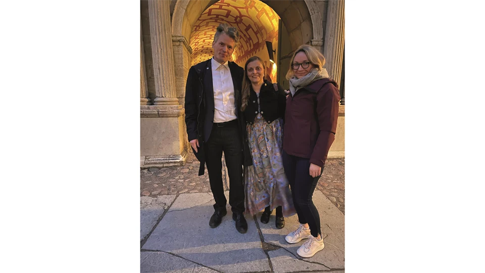 En man och två kvinnor står framför ett upplyst stenvalv. 