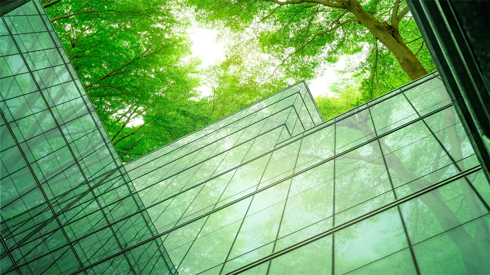 Ett abstrakt foto med gröna trädtoppar och glasväggar