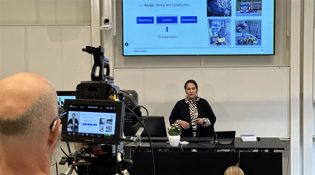 A man is filming a woman on a stage