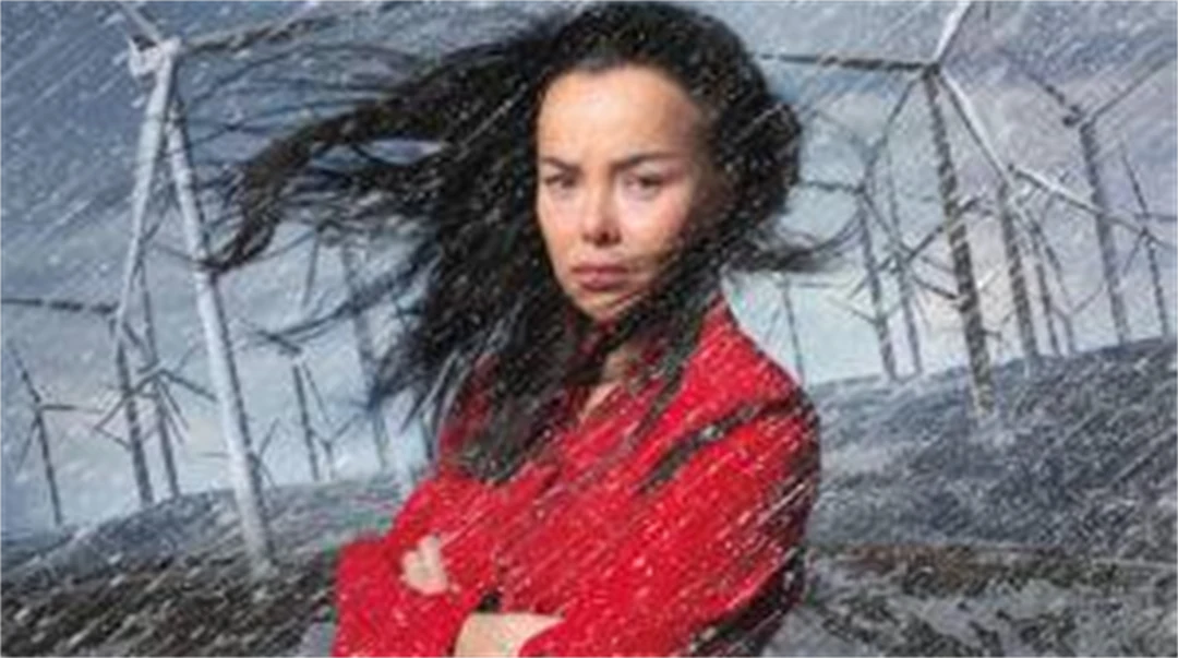 En kvinna i en storm framför vindkraftturbiner
