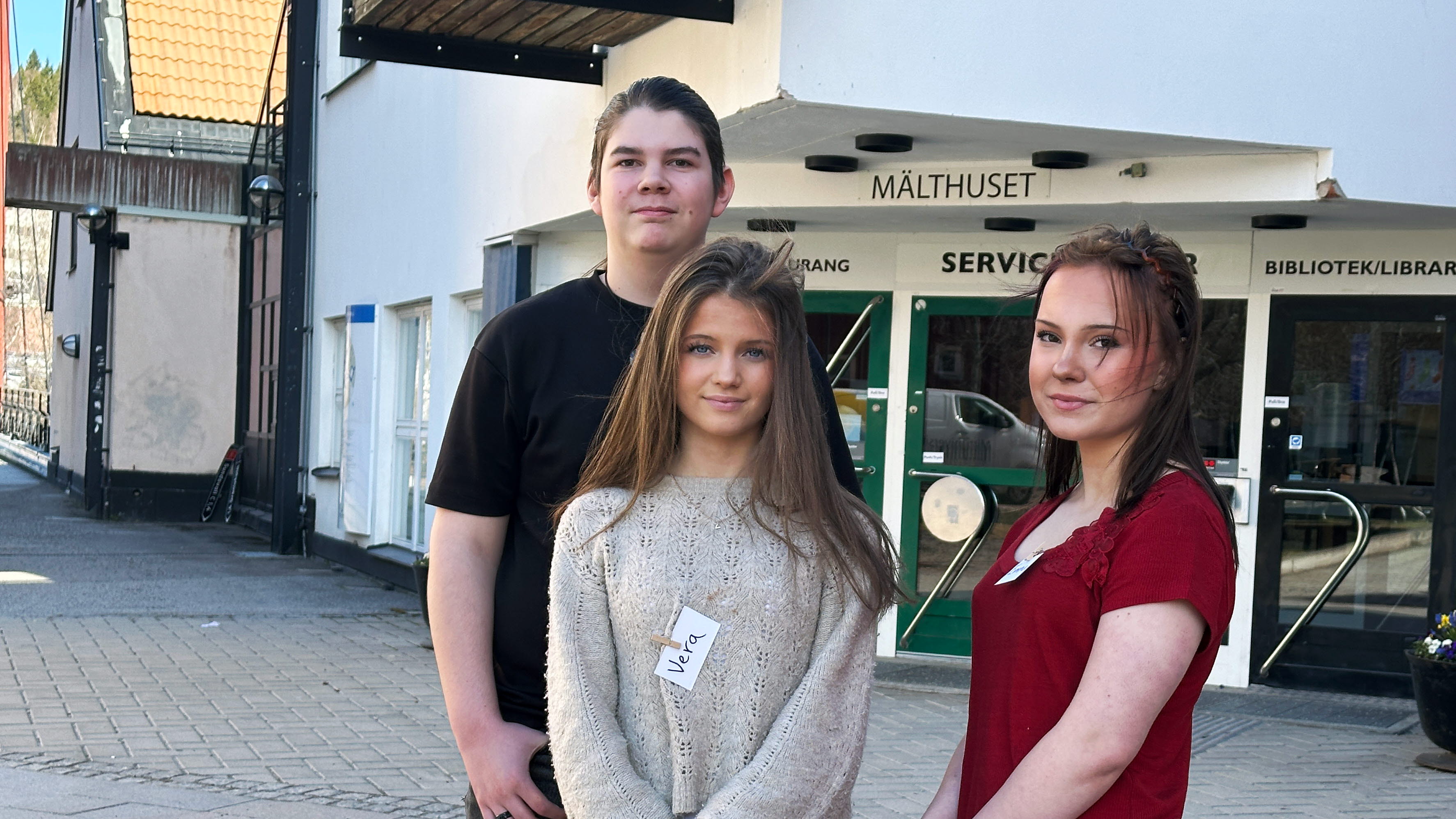 Tre ungdomar utanför en byggnad