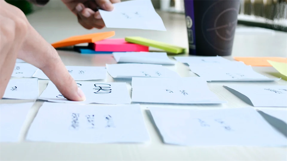 Två händer som ordnar post it lappar på ett bord