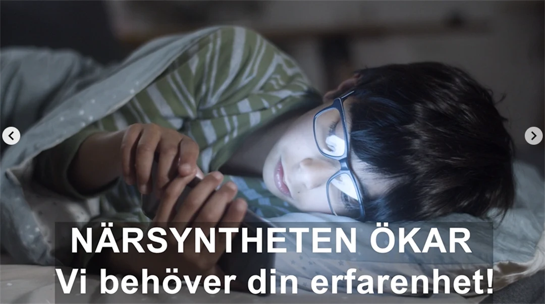 En pojke med glasögon ligger i sängen och tittar på sin mobil.