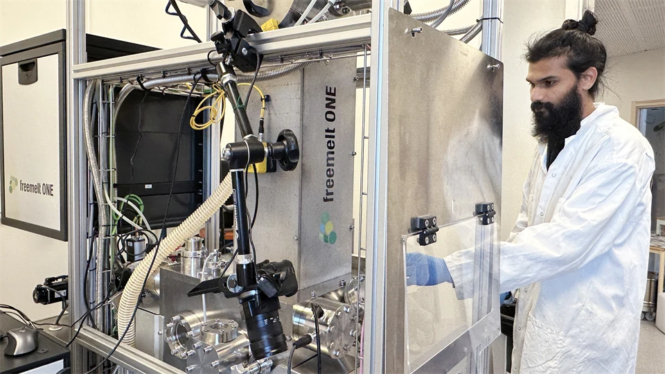 A man in a white lab coat, inside a lab.