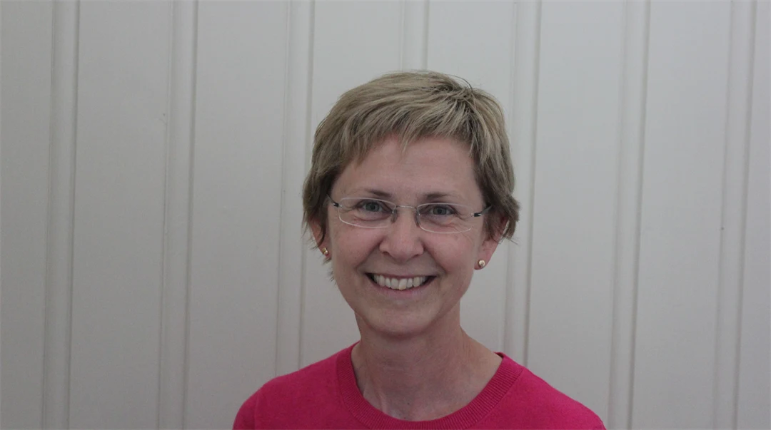 A portrait photo of a woman with short blonde hair and a red shirt