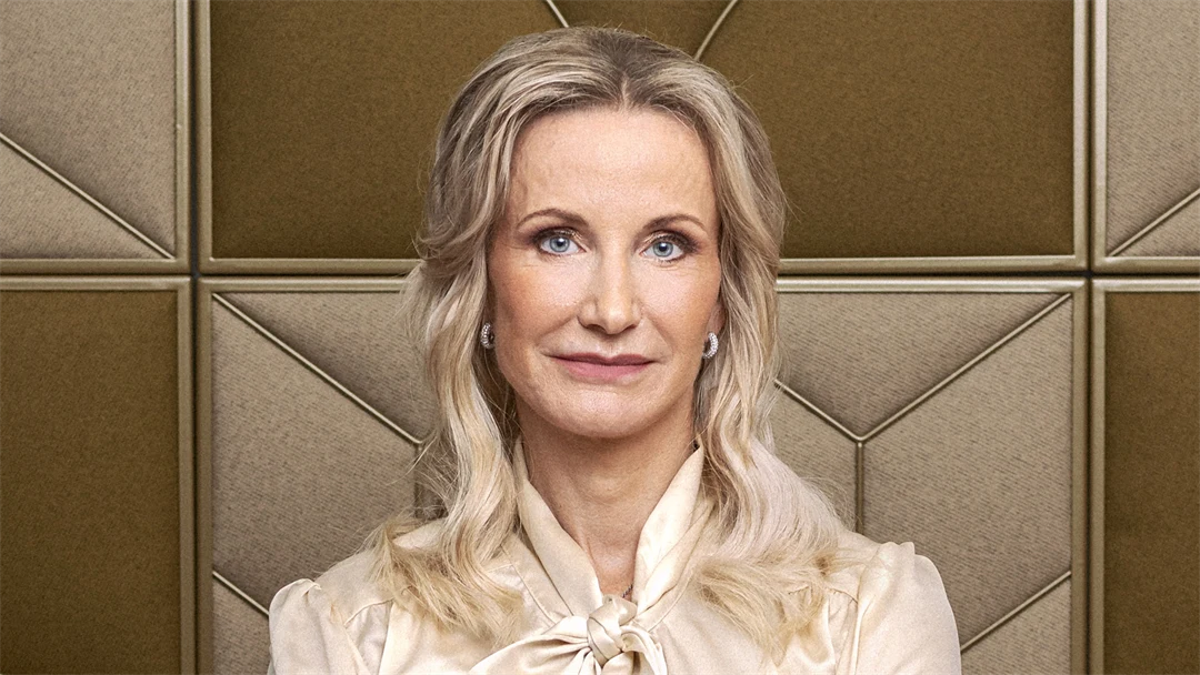 Porträttbild av kvinna med ljust hår och blus som står med armarna i kors.