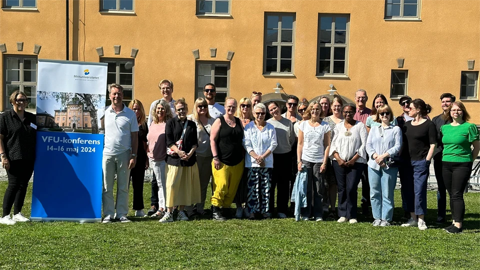 Gruppbild på gräsplan framför ett gult hus.