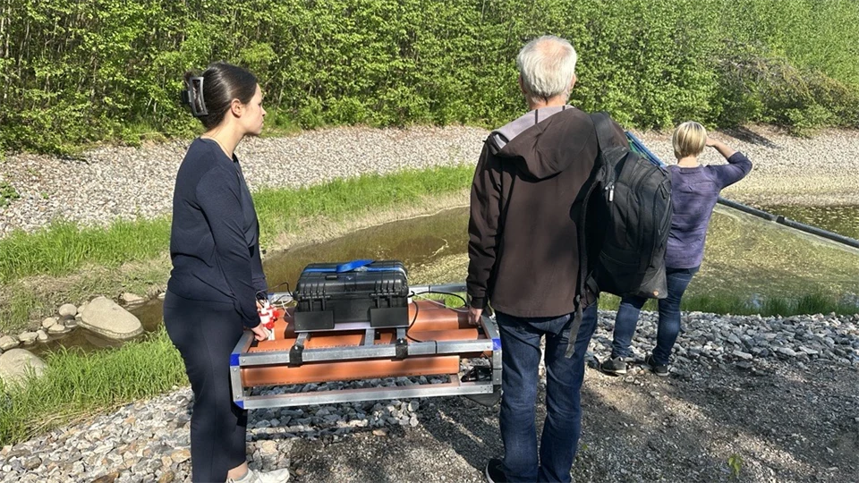 Två personer bär en liten orange båt som möter sedimentnivåer