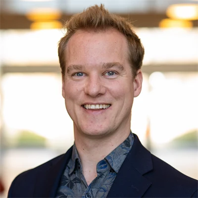 En man i blont hår och, blå skjorta och mörkblå kavaj.