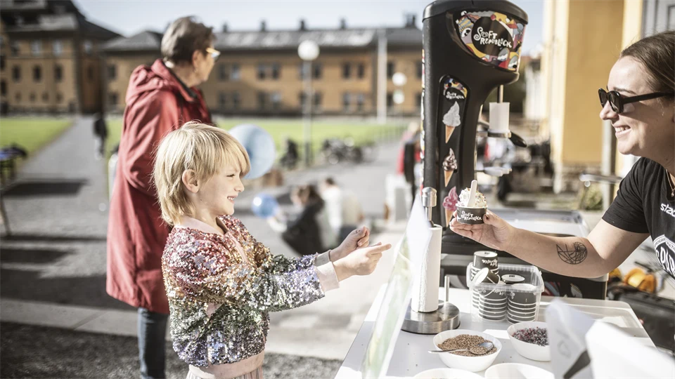 En liten pojke tar emot en mjukglass.