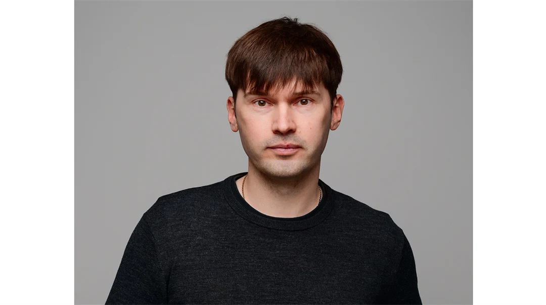 A man with dark, short hair, wearing a black shirt.