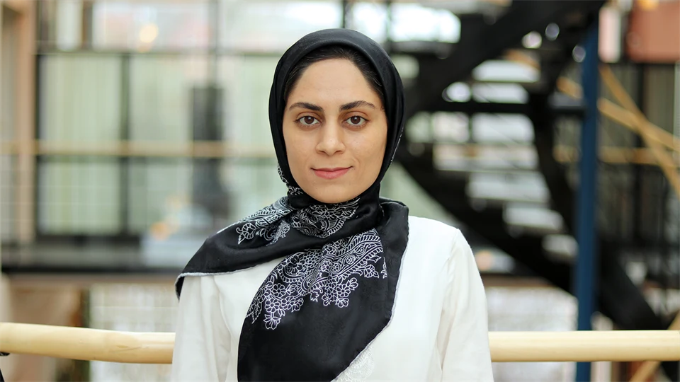 Woman in white sweater and black, white-patterned headscarf.
