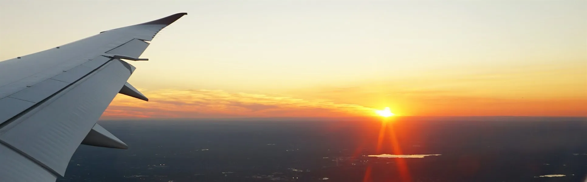 Flygplansvinge och solnedgång genom ett flygplansfönster