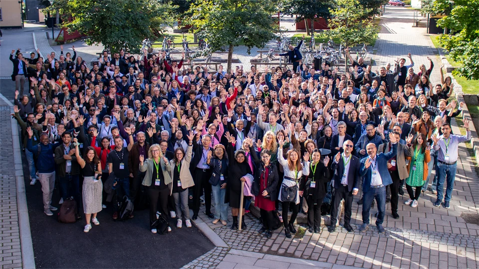 En stor grupp människor står tillsammans. De sträcker upp sina armar i luften.