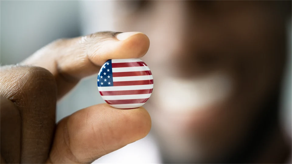En man håller upp en pin med den amerikanska flaggan på