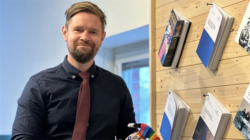 En man med blå skjorta och röd slips håller en hammare