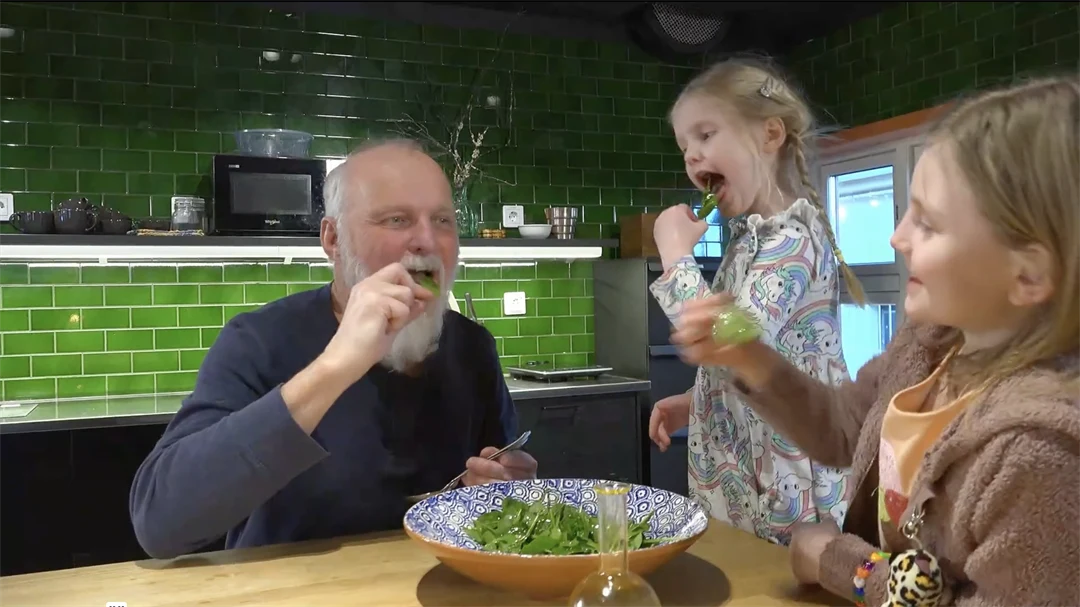 En man och två barn äter sallad