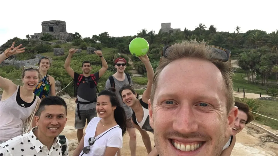 Axel Eriksson i förgrunden med en grupp glada människor bakom sig. I horisonten syns hus på en höjd.