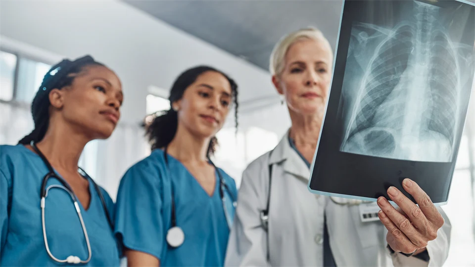 Sjuksköterskor och en läkare som tittar på en röntgenplåt. 