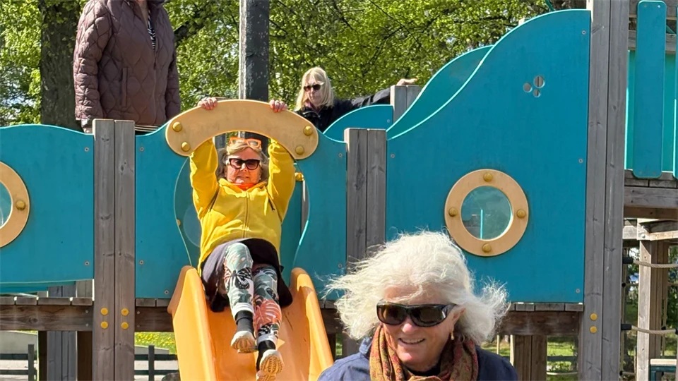 Äldre kvinnor åker rutschkana på lekplats.