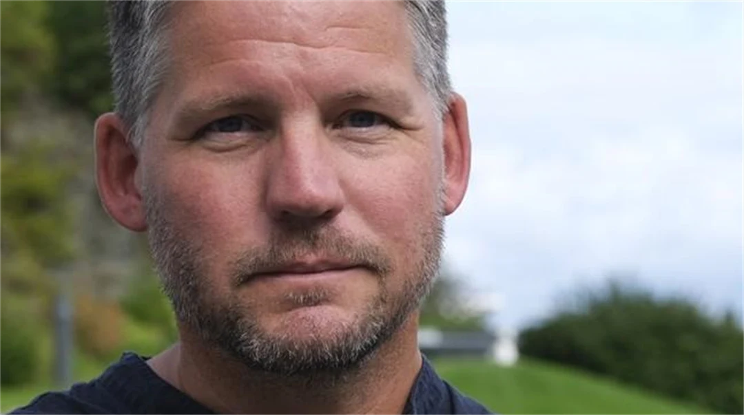 A portrait photo of a man with short hair and a blue t-shirt
