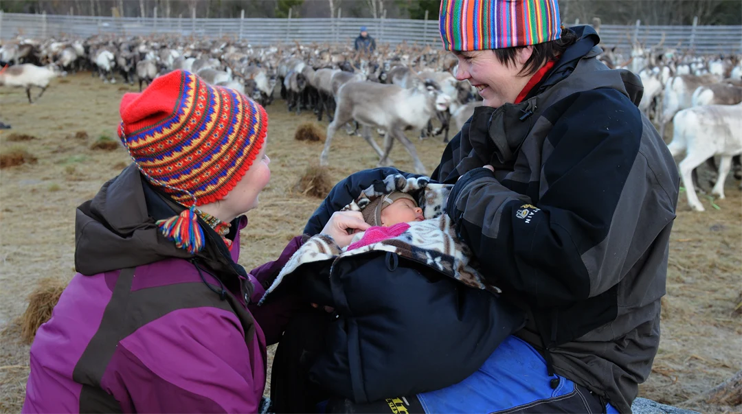Kvinna med två barn i ett rengärde.