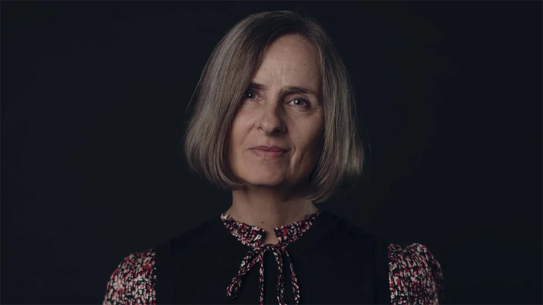 Porträtt av en kvinna mot svart bakgrund.