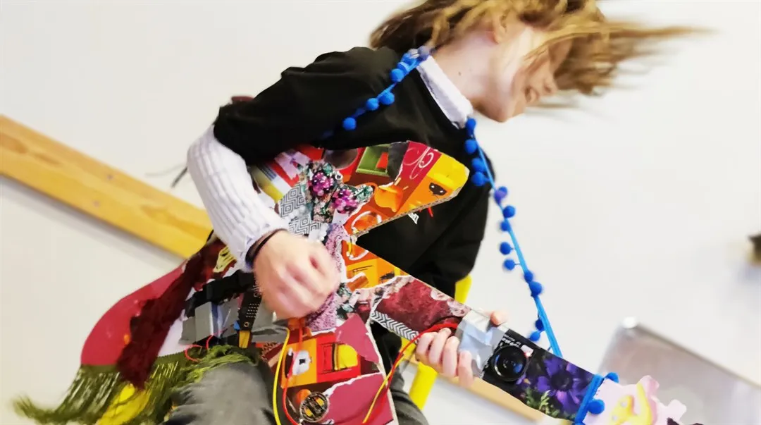 Tjej spelar egenprogrammerad gitarr med kollage