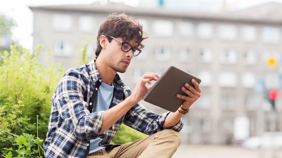 Man sits outside and study with a tablet.