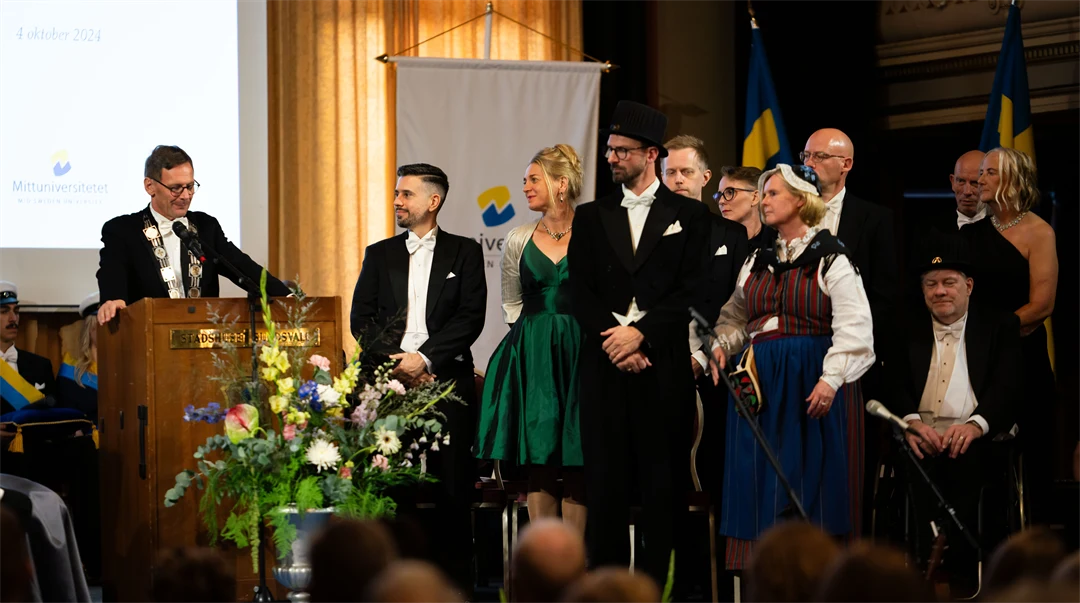 En grupp finklädda människor står på en scen.