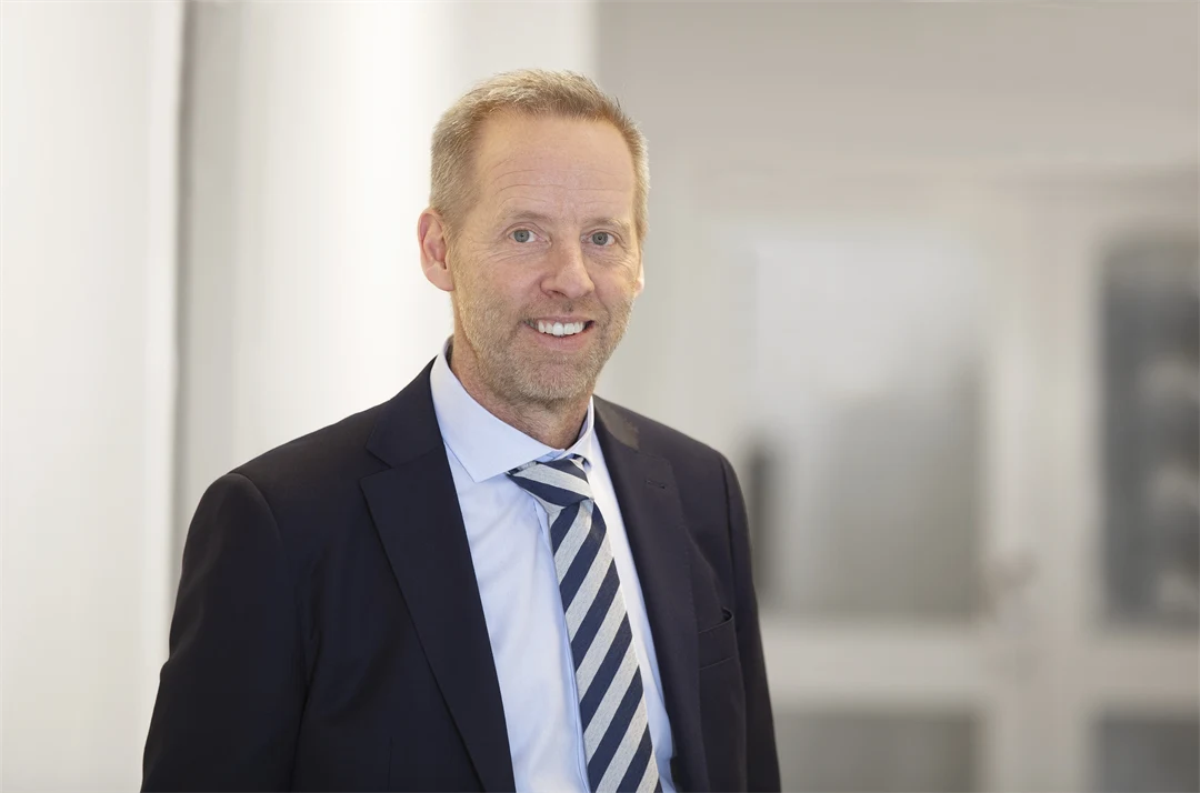 A man in a jacket in front of a white glass door
