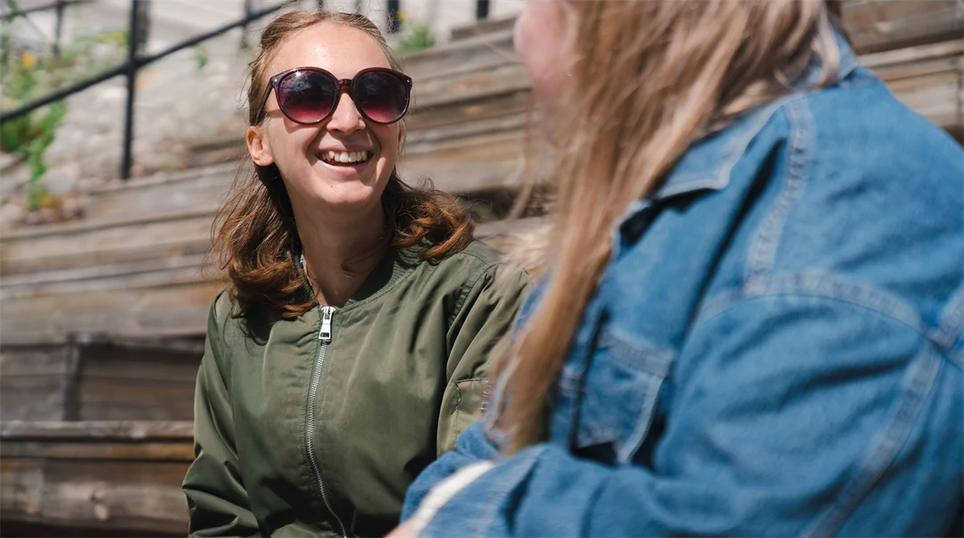 Två studenter som sitter och pratar i en trappa. 