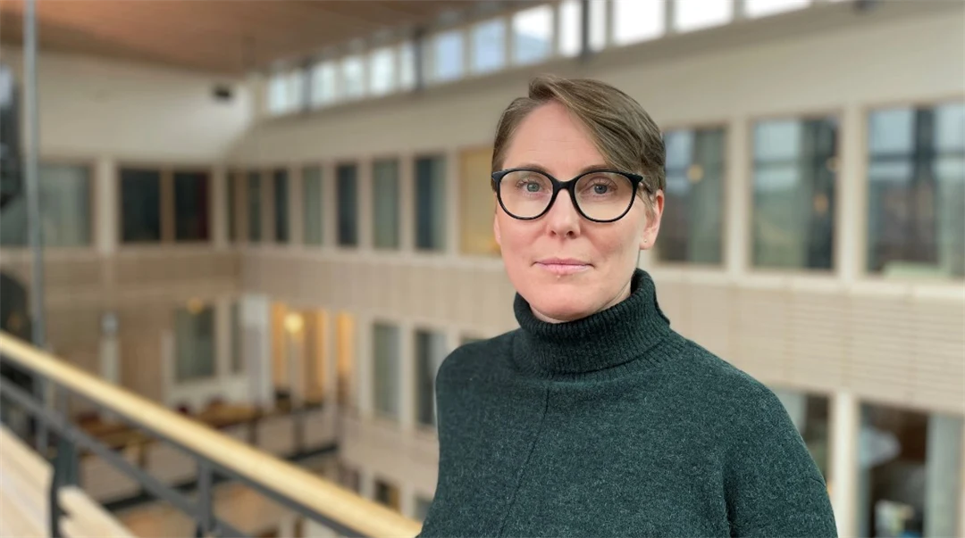 Porträttfoto av en kvinna med brunt hår och svarta glasögon