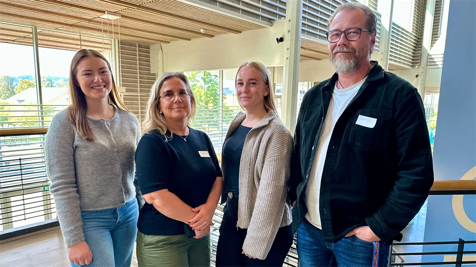 Tre kvinnor och en man ler mot kameran