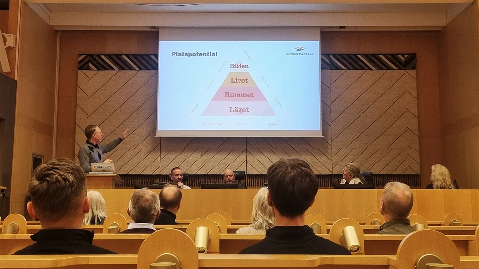 Människor sittandes i en föreläsningssal, lyssnandes till en föreläsare