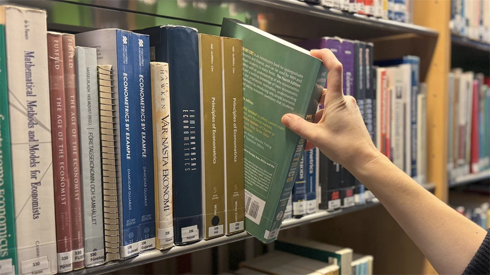 en hand tar böcker i bokhylla