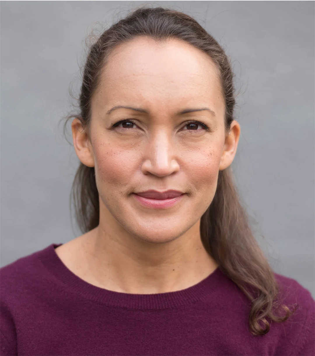 en kvinna ler och tittar in i kameran