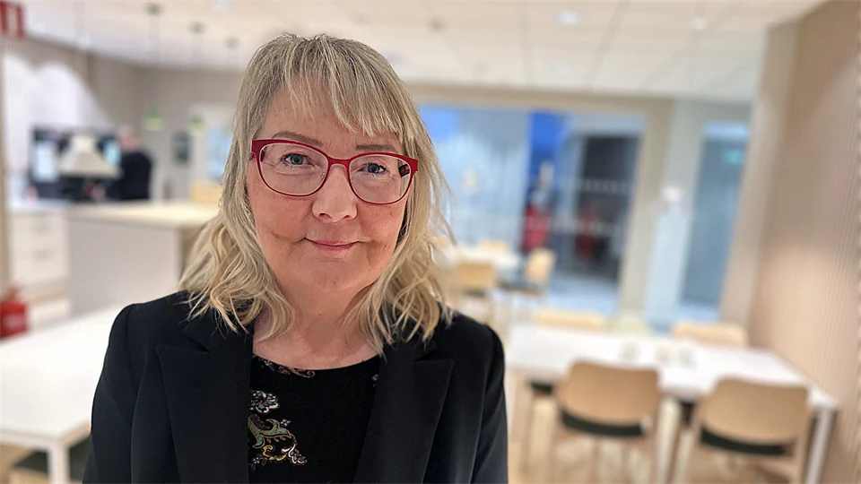 En kvinna med glasögon står i ett kök