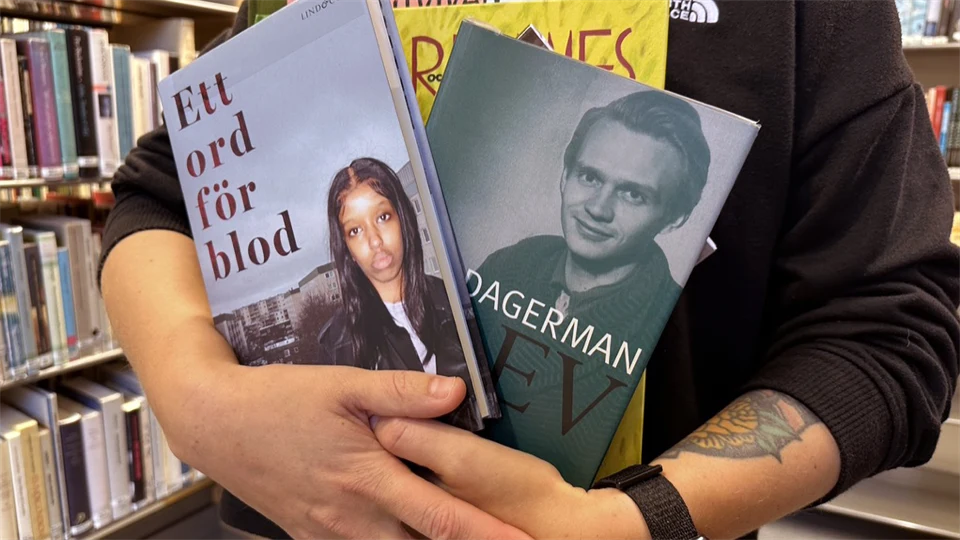 En person håller böcker i sin famn i ett bibliotek