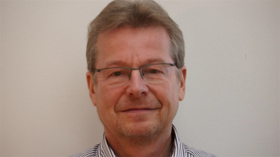 An older man with glasses and a shirt on.